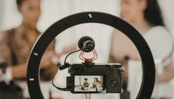 Two women interviewing in front of a ring light and camera. 