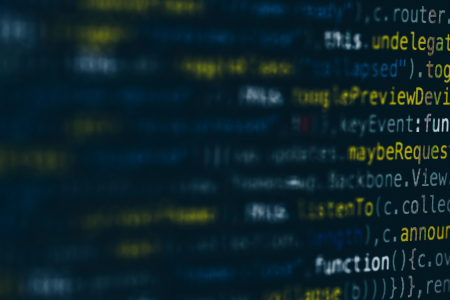 A blurred background of computer code and text in dark blue, white and yellow font. 